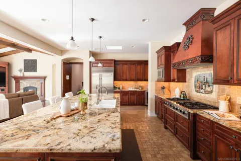a kitchen with stainless steel appliances granite countertop a stove top oven a refrigerator a sink and a dining table with chairs