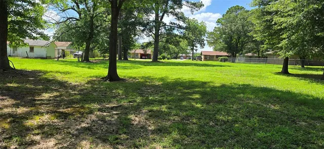 a view of a house with a big yard and large trees