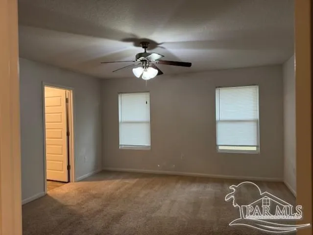 an empty room with windows and fan