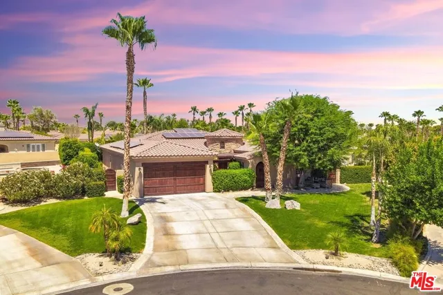 a front view of a house with a yard and palm trees