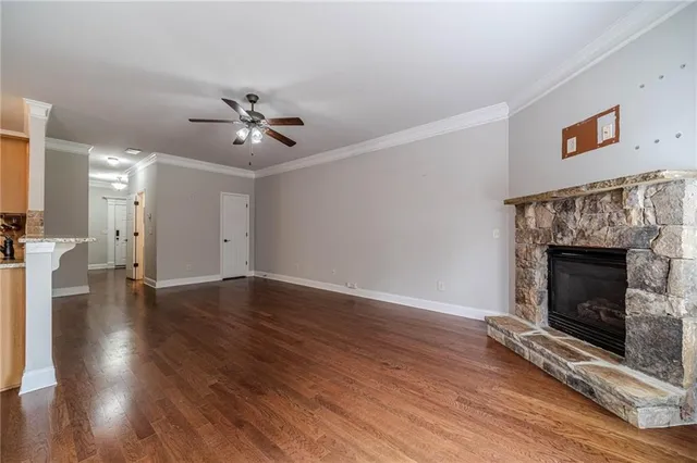 a view of an empty room with wooden floor a fireplace and a window
