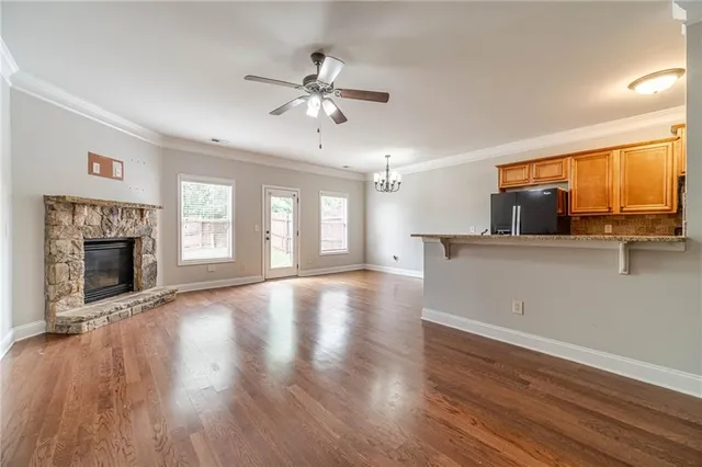 a view of an empty room with wooden floor and a fireplace