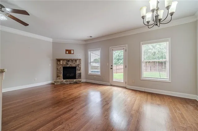 an empty room with wooden floor fireplace and windows