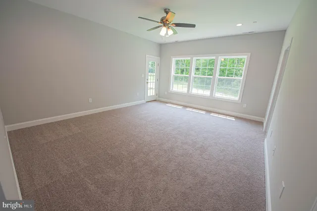 an empty room with a window and a ceiling fan