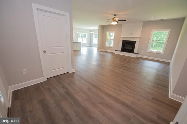 an empty room with wooden floor fireplace and windows