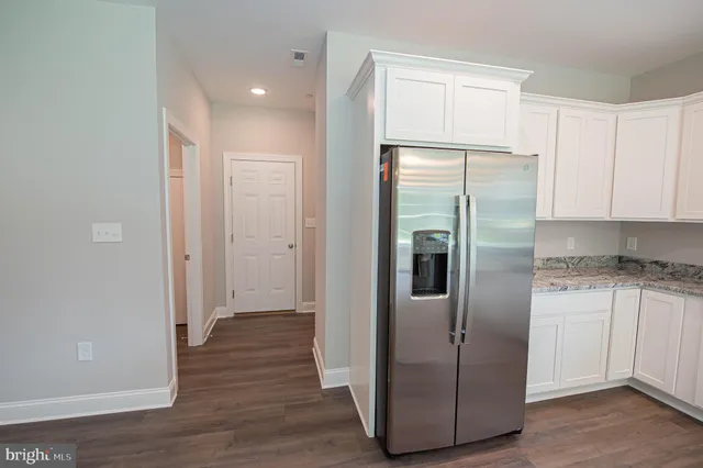 a view of a refrigerator in kitchen and white cabinets