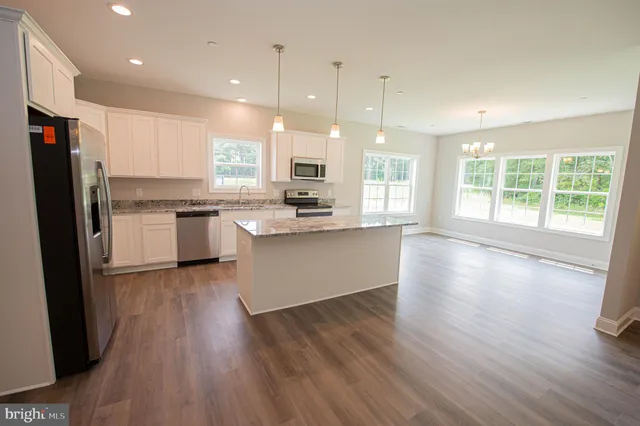 a large kitchen with stainless steel appliances granite countertop a stove a sink a refrigerator and a large window