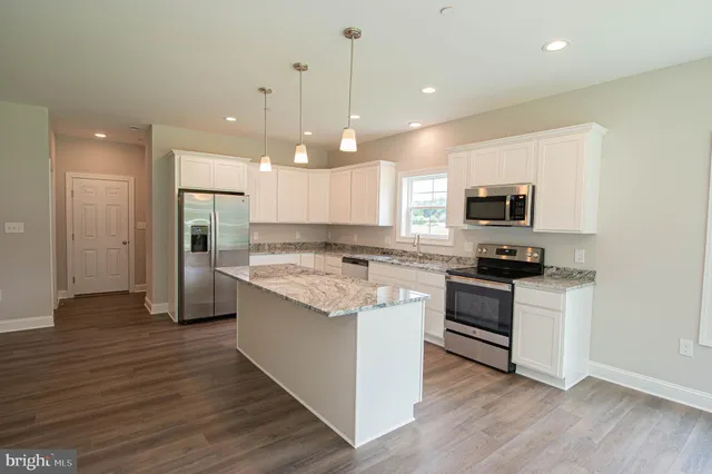 a kitchen with kitchen island granite countertop a sink cabinets and wooden floor