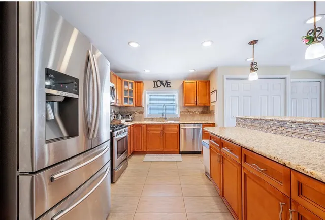 a kitchen with stainless steel appliances granite countertop a refrigerator oven a sink dishwasher and white cabinets with wooden floor