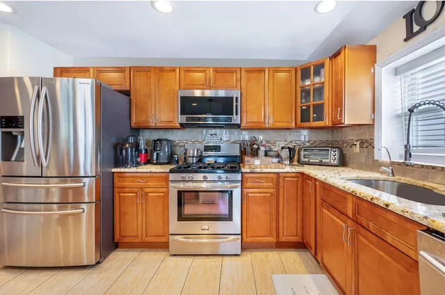 a kitchen with stainless steel appliances granite countertop a stove a sink and a refrigerator