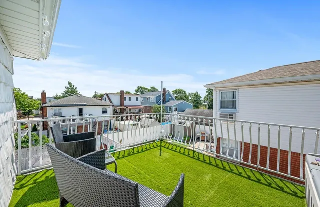 a view of a balcony with two couches chairs and wooden fence