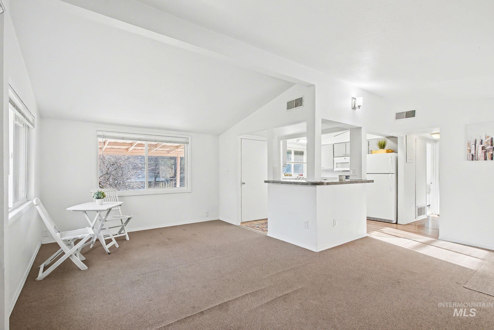 150 Elm Street Orofino, ID 83544 - Photo 11 of 36 Bright living area featuring vaulted ceilings, a kitchen pass-through with a breakfast bar, recessed wall lighting, and natural light from multiple windows