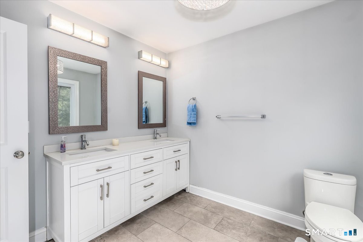 127 Putnam Park Road Bethel, CT 06801 - Photo 15 of 35 a bathroom with a toilet a double vanity sink and a mirror