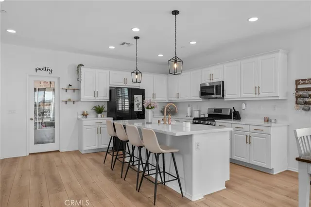 a kitchen with stainless steel appliances kitchen island a white cabinets and wooden floor
