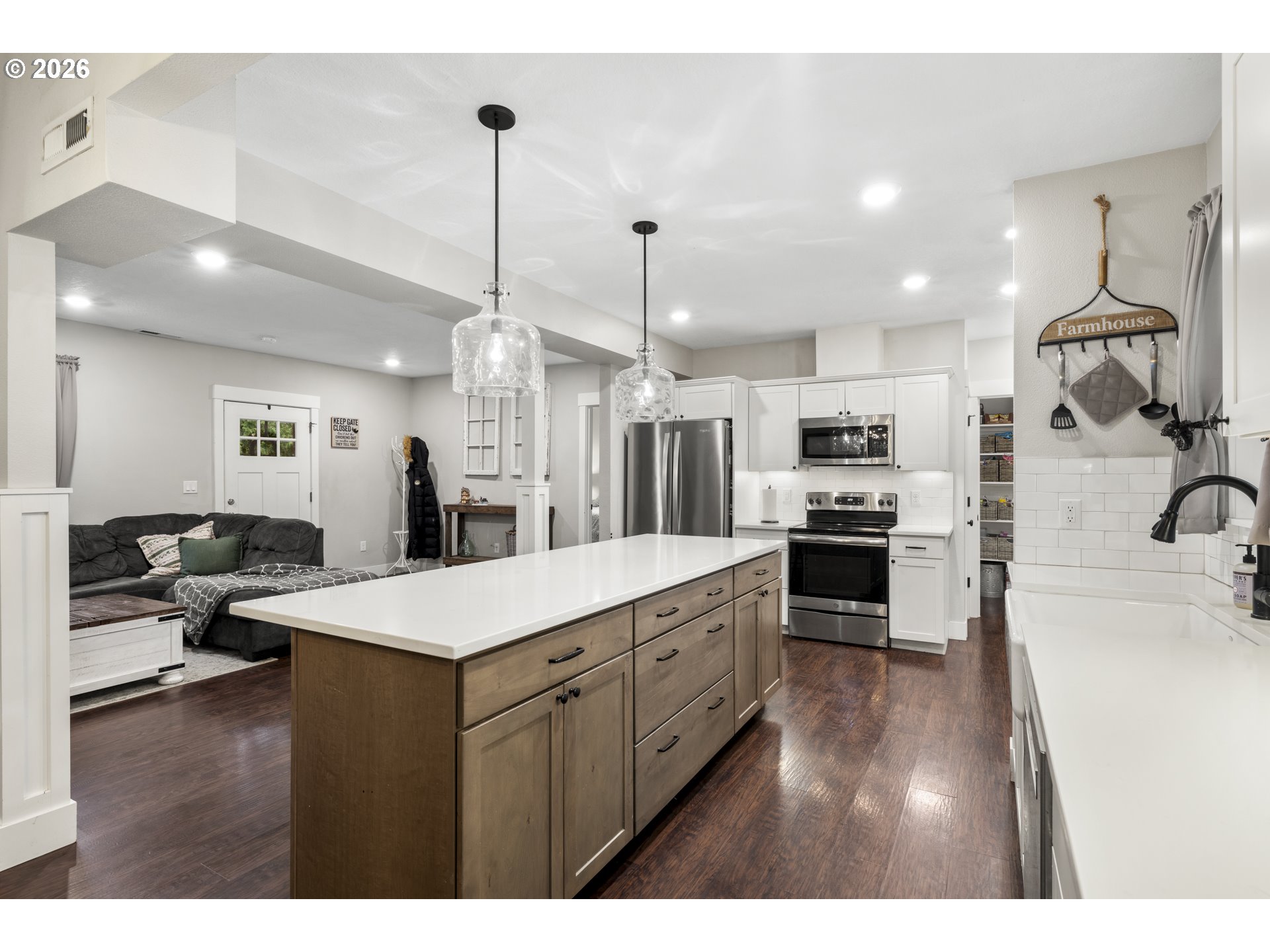 16453 Forsythe Road Oregon City, OR 97045 - Photo 15 of 48 a large kitchen with kitchen island a stove a sink a refrigerator white cabinets and couches with wooden floor