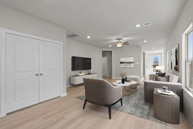 a living room with furniture a flat screen tv and a window