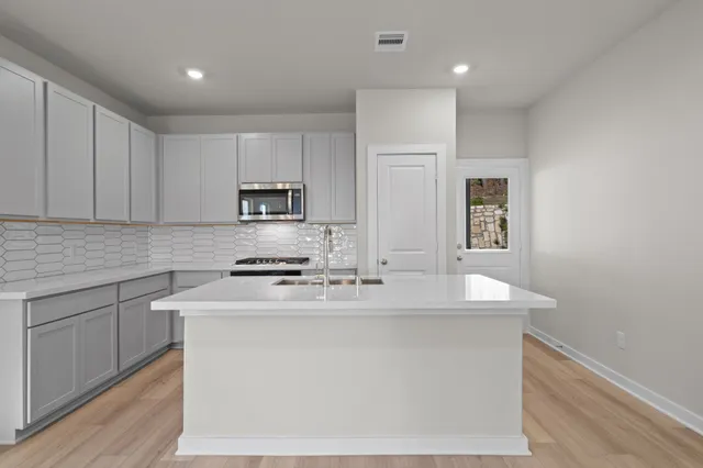 a kitchen with kitchen island a sink stainless steel appliances and cabinets