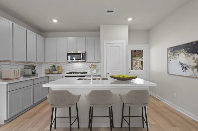 a kitchen with stainless steel appliances granite countertop a stove a sink a microwave a stove and white cabinets