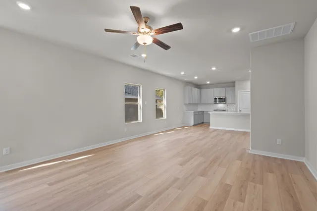 an empty room with wooden floor and windows