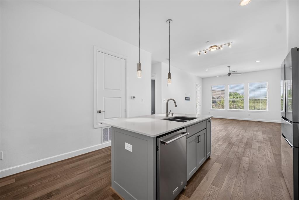 5015 Meridian Lane, Unit 2102 Addison, TX 75001 - Photo 7 of 36 Kitchen island with light gray cabinetry, integrated stainless steel dishwasher, and a double basin sink with a high-arc faucet