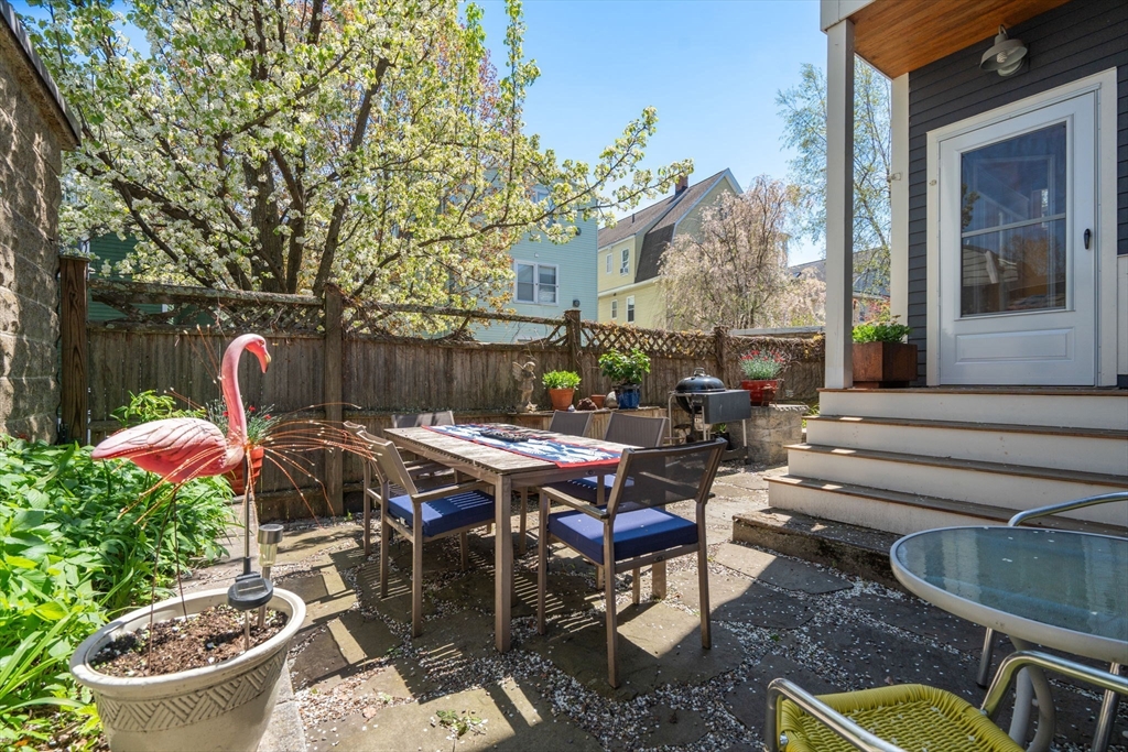 45 Springfield Street, Unit 1 Belmont, MA 02478 - Photo 21 of 27 a view of a patio with table and chairs potted plants and a large tree