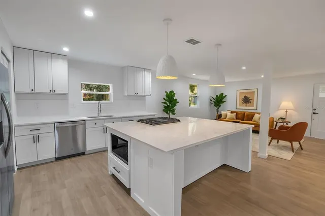 a large white kitchen with a stove a sink a refrigerator and cabinets