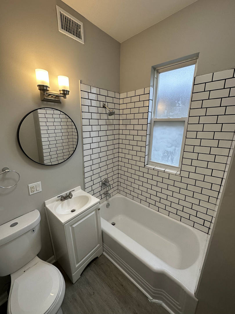 6320 South Drexel Avenue, Unit 3 Chicago, IL 60637 - Photo 9 of 13 a bathroom with a toilet a sink a mirror and bathtub