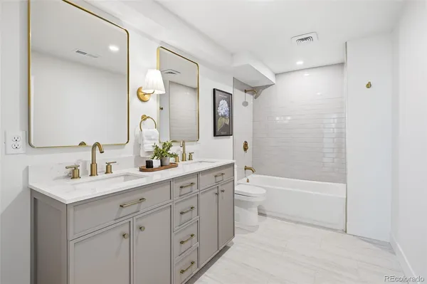 a bathroom with a toilet a sink a tub and a mirror