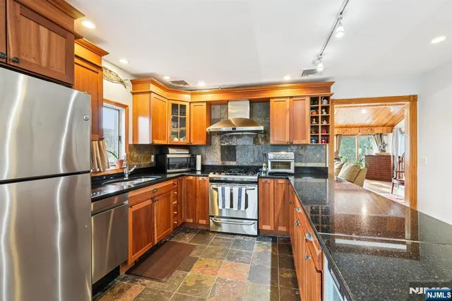 a kitchen with stainless steel appliances granite countertop a refrigerator a stove and a sink