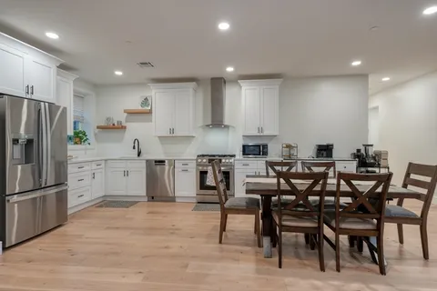a kitchen with stainless steel appliances kitchen island granite countertop a table chairs and a refrigerator