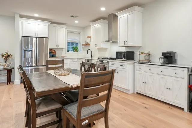 a kitchen with stainless steel appliances granite countertop a dining table chairs refrigerator and cabinets