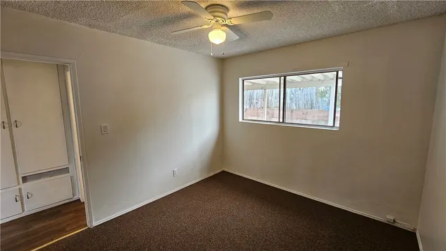 an empty room with windows and fan