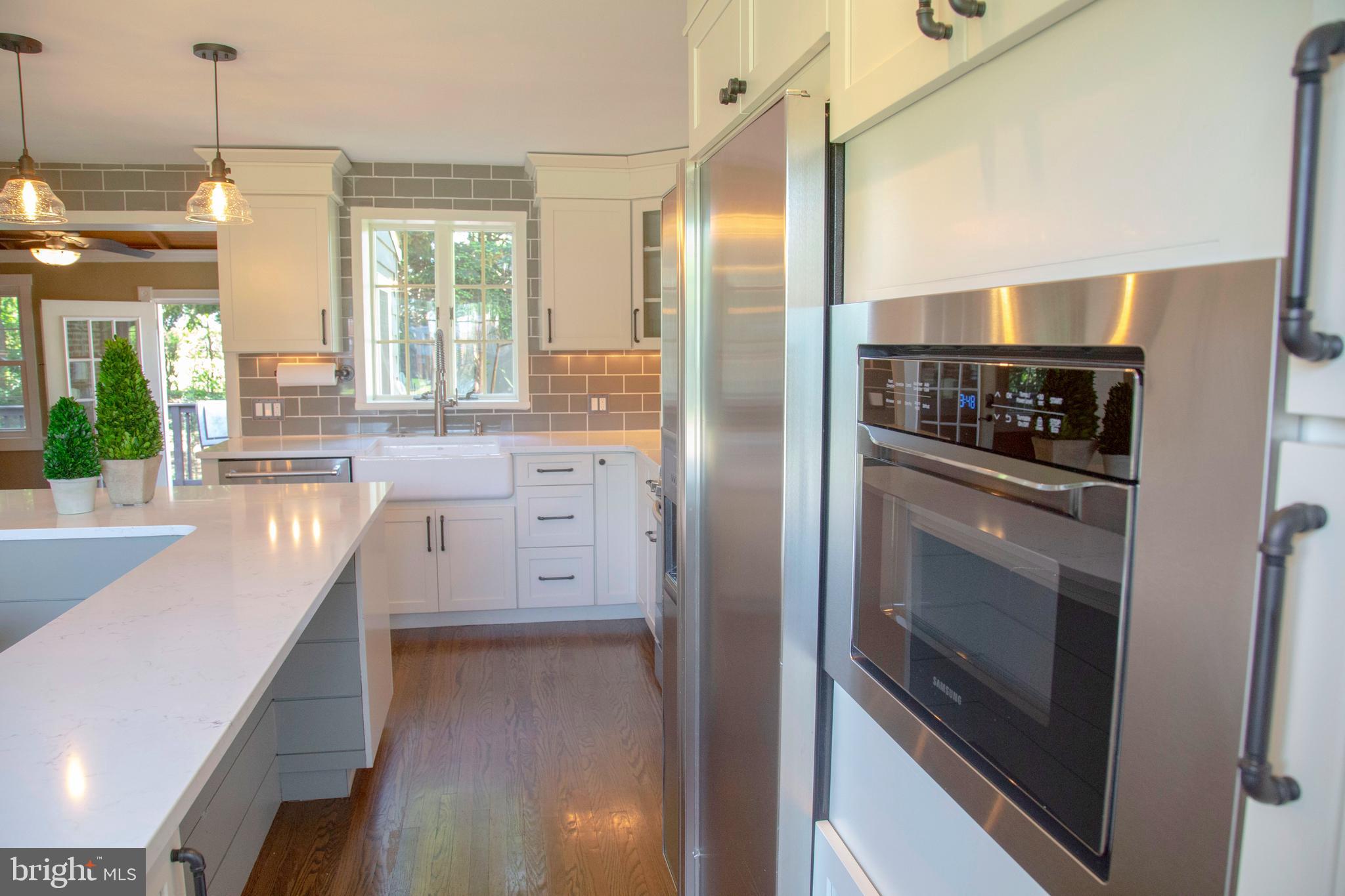 584 Valley View Road Springfield, PA 19064 - Photo 8 of 38 a kitchen with stainless steel appliances granite countertop a refrigerator a oven and white cabinets with wooden floor