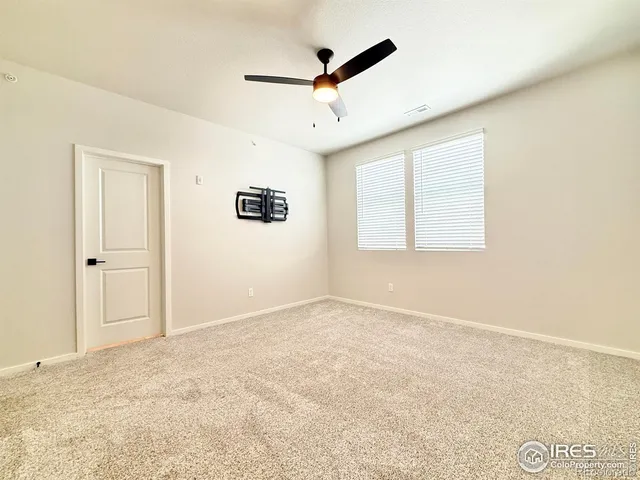 an empty room with windows and ceiling fan