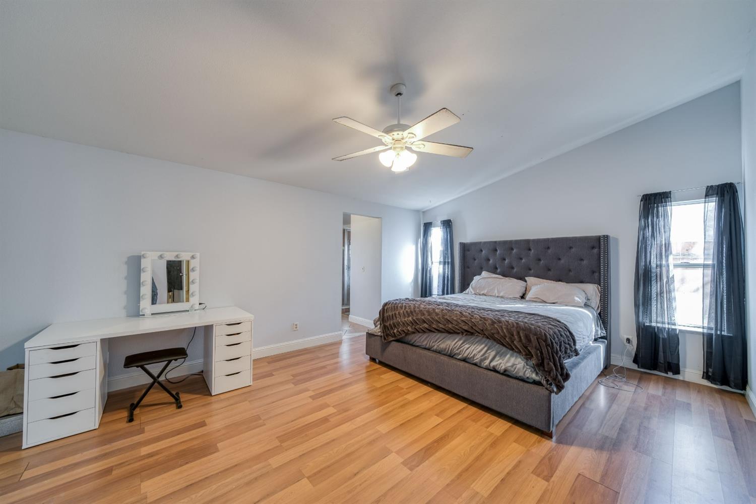 2505 Stuart Avenue Clovis, CA 93611 - Photo 12 of 23 a spacious bedroom with a bed a chandelier and a couch