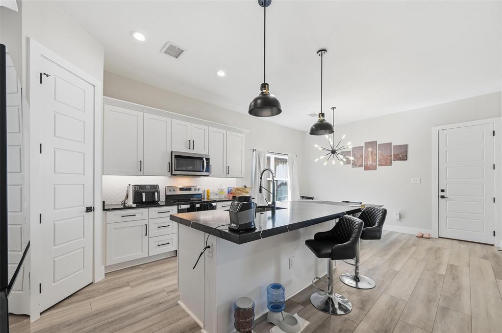 7733 Indian Ridge Trail Dallas, TX 75232 - Photo 6 of 30 a kitchen with stainless steel appliances kitchen island granite countertop a sink dishwasher a microwave oven a stove with white cabinets and wooden floor