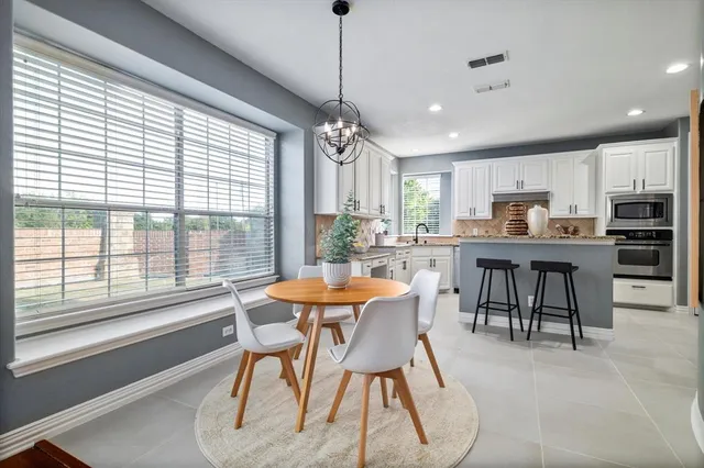a dining room with stainless steel appliances granite countertop furniture a large window and a kitchen view