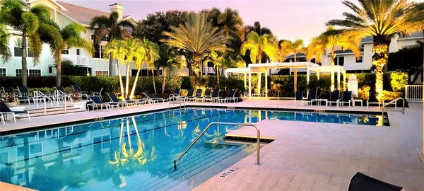 a view of a swimming pool with a table and chairs under palm trees