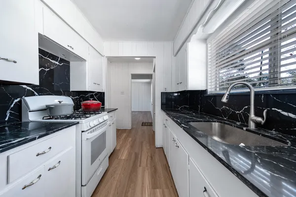 a kitchen with granite countertop a sink and a stove top oven