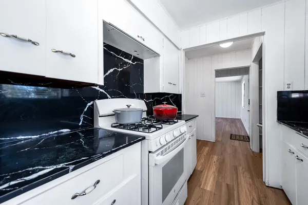 a kitchen with a sink stove and wooden floor