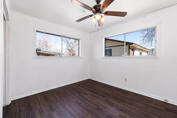 a view of empty room with wooden floor and fan