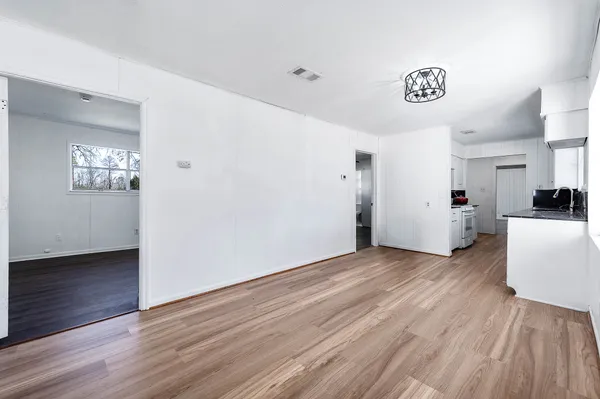 a view of a room with wooden floor kitchen view and a window