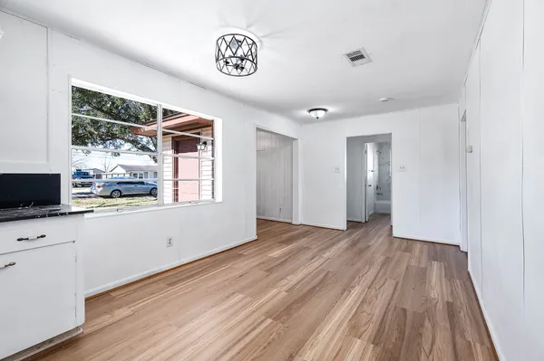 a view of empty room with wooden floor and fan