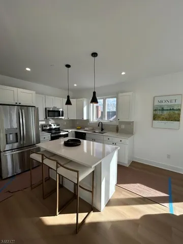 a kitchen with stainless steel appliances kitchen island granite countertop a sink a stove and refrigerator