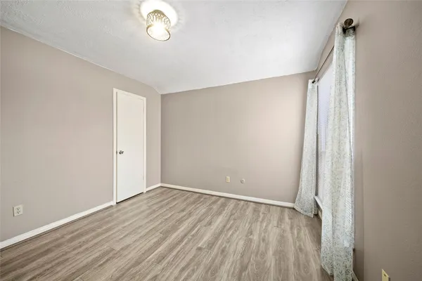 an empty room with wooden floor and fan