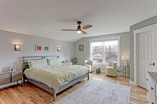 a bedroom with a large bed and a chandelier fan