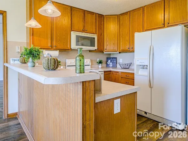 a kitchen with stainless steel appliances granite countertop a refrigerator a sink a stove a washer and dryer with wooden floor