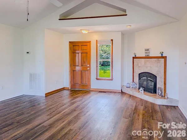a view of empty room with fireplace and wooden floor