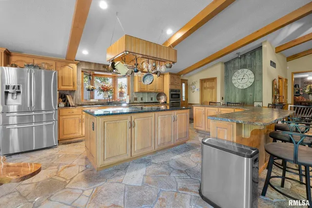 a large kitchen with stainless steel appliances granite countertop a large counter top a stove a chimney a sink and a large window