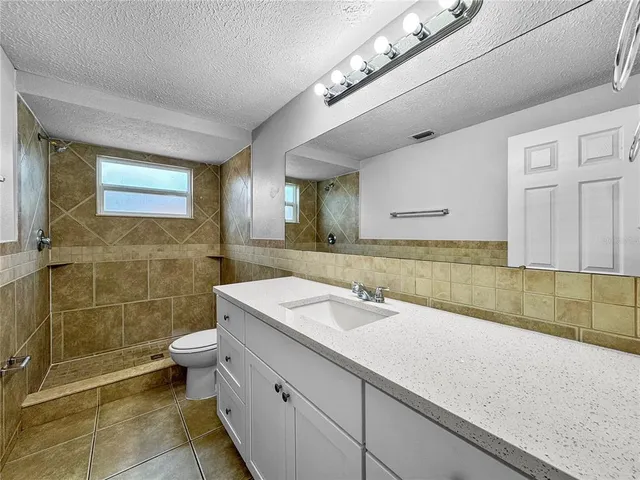 a bathroom with a granite countertop bathtub sink vanity and toilet